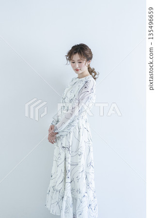 A young woman wearing a dress standing against a white background A young woman wearing a dress standing against a white background 135496659