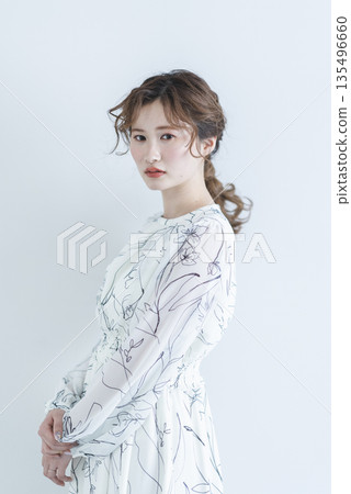 A young woman wearing a dress standing against a white background A young woman wearing a dress standing against a white background 135496660