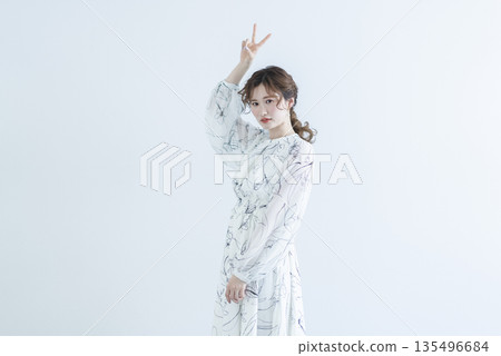 A young woman wearing a dress standing against a white background 135496684