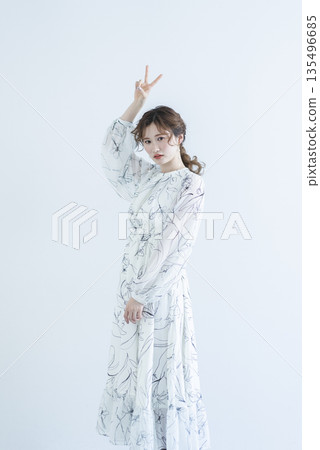 一位身穿洋裝的年輕女子站在白色背景上 135496685