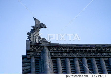 日本岡山城天守閣屋頂的黑色鯱瓦特寫與藍天背景 烏城傳統建築裝飾細節 日本岡山城天守閣屋頂的黑色鯱瓦特寫與藍天背景 烏城傳統建築裝飾細節 135497112