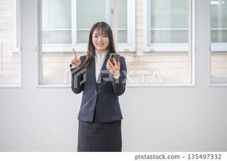 Business woman pointing at smartphone Business woman pointing at smartphone 135497332