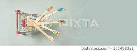 Eco-friendly bamboo toothbrushes in small shopping cart on light background Eco-friendly bamboo toothbrushes in small shopping cart on light background 135498351
