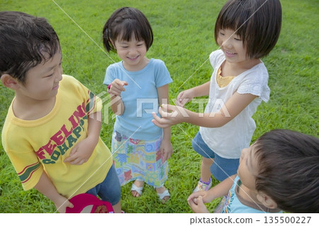 Children looking at grasshoppers they caught in the park Children looking at grasshoppers they caught in the park 135500227