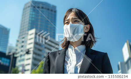 Japanese women wearing masks going out in business districts and under cherry blossoms. Image of health management and infection prevention. 135500234