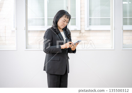 A businesswoman touching her smartphone with a sad face 135500312