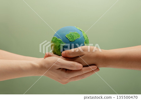 Two people holding Globe together. Environmental awareness, sustainability, nature protection Two people holding Globe together. Environmental awareness, sustainability, nature protection 135500470
