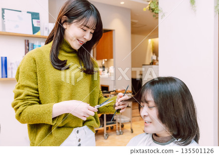 Female hairdresser cutting hair at beauty salon 135501126