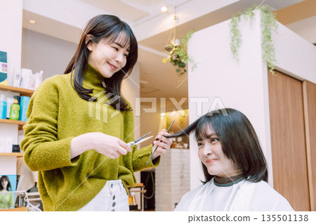 Female hairdresser cutting hair 135501138