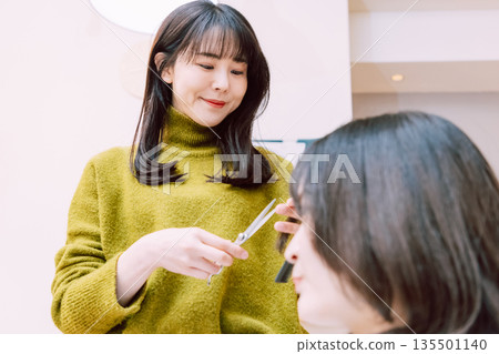 Female hairdresser cutting hair at beauty salon 135501140