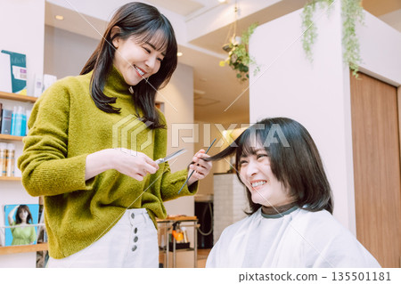 Female hairdresser cutting hair at beauty salon Female hairdresser cutting hair at beauty salon 135501181