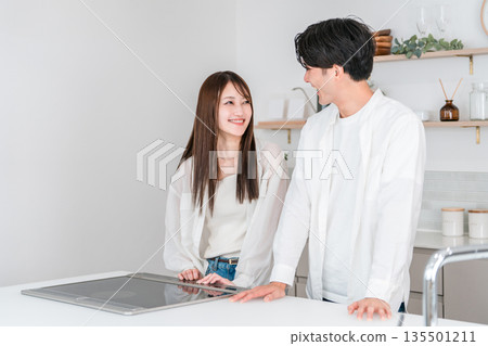 A young couple looking at the model room of a house builder, the kitchen of a showroom A young couple looking at the model room of a house builder, the kitchen of a showroom 135501211