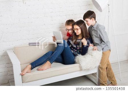 Group of kids in eye glasses look into tablet. Children computer games, social networks and media addiction concept. Girl and boys with gadget. Communication technologies. Group of kids in eye glasses look into tablet. Children computer games, social networks and media addiction concept. Girl and boys with gadget. Communication technologies. 135501438