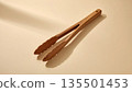 Wooden tongs arranged on a beige background 135501453