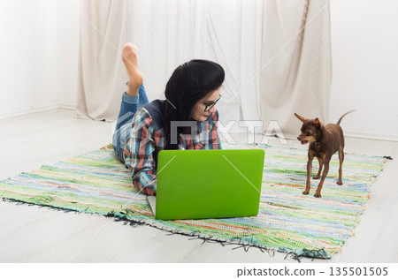 Girl at home with laptop and dog chihuahua. Hipster freelancer woman works at home. Home office, freelance. 135501505