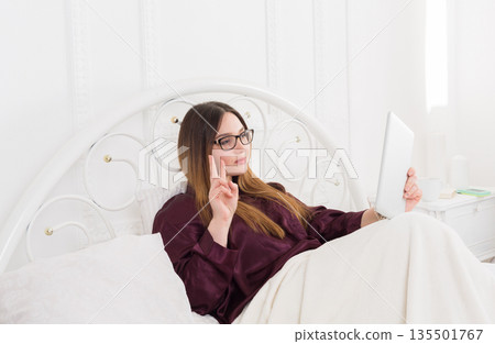 Sunday morning in bed. Young woman making selfie for social networks in bed. Communication, internet addiction concept 135501767