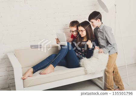 Group of kids in eye glasses look into tablet. Children computer games, social networks and media addiction concept. Girl and boys with gadget. Communication technologies. 135501796