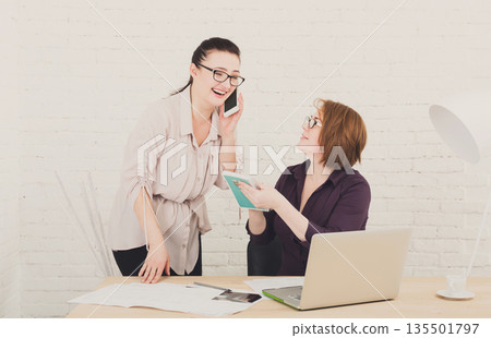 Women have fun in office. Teamwork, friendly business communication. Middle-aged architects designers discuss project. Female coworkers. 135501797