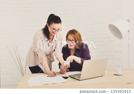 Two women in the office. Teamwork, business communication. Middle-aged architects designers in team work discuss project. Start up discussion. Female coworkers. 135501915