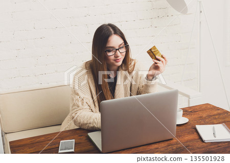 Online shopping at home. Girl holding credit card looking at laptop. buying in internet, e-commerce concept. Online shopping at home. Girl holding credit card looking at laptop. buying in internet, e-commerce concept. 135501928