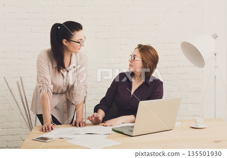 Two women in the office. Teamwork, business communication. Middle-aged architects designers in team work discuss project. Start up discussion. Female coworkers. Two women in the office. Teamwork, business communication. Middle-aged architects designers in team work discuss project. Start up discussion. Female coworkers. 135501930