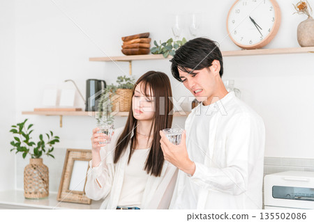A young Asian couple having trouble with bad-tasting tap water in the kitchen 135502086