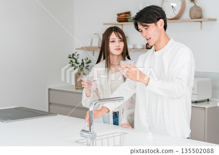 A young Asian couple having trouble with bad-tasting tap water in the kitchen 135502088