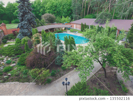 Modern hotel and spa. Landscape design of resort territory. Beautiful trees and bushes near pool, decor of park and garden. Modern hotel and spa. Landscape design of resort territory. Beautiful trees and bushes near pool, decor of park and garden. 135502116