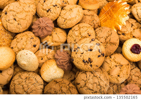 Cookies background. Sweet chocolate chips biscuits, shortbread with jam texture background. Oatmeal, chocolated drops and other sweets. Cookies background. Sweet chocolate chips biscuits, shortbread with jam texture background. Oatmeal, chocolated drops and other sweets. 135502165