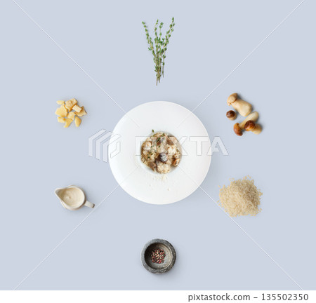 Risotto with wild mushrooms ingredients flat lay, isolated on blue background. Rice, fungus, sauce, parmesan and other ingredients around plate with dish ready 135502350
