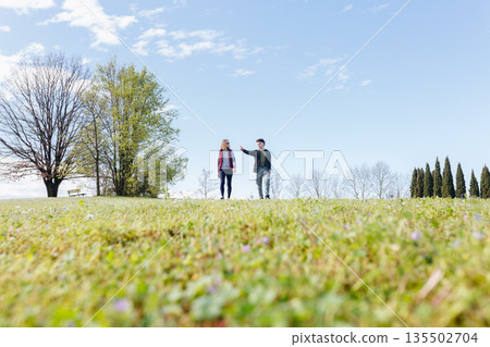 wide angle view of two persons walking together in the park and talking 135502704