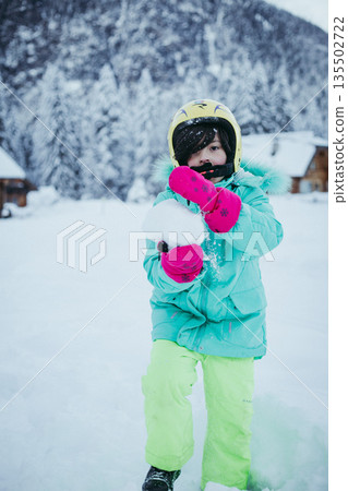 a child preparing a snowball for launching a child preparing a snowball for launching 135502722