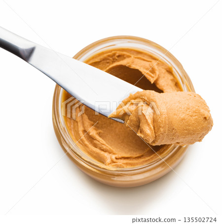 Jar with peanut butter and knife butter smear isolated on white background. Ameriacan dessert concept 135502724