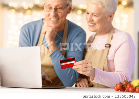 Christmas Grocery Shopping Online. Senior Couple Using Laptop And Credit Card Ordering Food In Kitchen At Home. Internet Banking, Shop Groceries Distantly. Shallow Depth, Selective Focus, Cropped 135503042