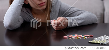 Hopeless young woman with depression planning to commit suicide by overdosing on meds at home. Desperate lady having nervous breakdown, feeling stressed, going through existential crisis 135503086