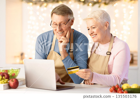 Grocery Christmas Offer. Happy Senior Couple With Laptop And Credit Card Shopping Buying Food Online In Modern Kitchen At Home. Elderly Spouses Ordering And Paying Via Internet Banking. Grocery Christmas Offer. Happy Senior Couple With Laptop And Credit Card Shopping Buying Food Online In Modern Kitchen At Home. Elderly Spouses Ordering And Paying Via Internet Banking. 135503176