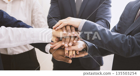 Corporate cooperation. Stacked hands of multiethnic business team, panorama 135503254