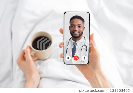Woman Having Video Call With Doctor Lying In Bed At Home. Online Medical Consultation Concept. Virtual Clinic Helpline And Mobile Healthcare App. Physician Consulting Patient Distantly. Cropped Woman Having Video Call With Doctor Lying In Bed At Home. Online Medical Consultation Concept. Virtual Clinic Helpline And Mobile Healthcare App. Physician Consulting Patient Distantly. Cropped 135503405