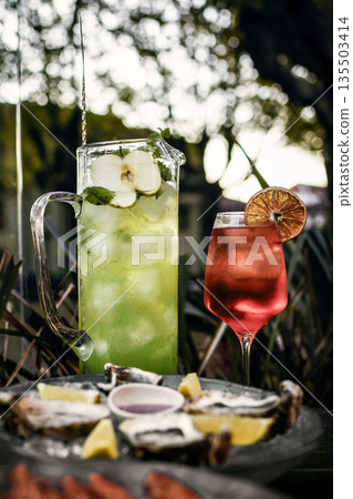 Mixed cocktail drinks and sangria with snacks on restaurant table outdoors at sunset 135503414