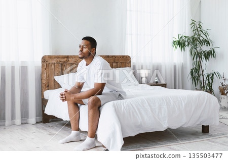 Thoughtful African American Man Thinking Sitting On Bed In Bedroom At Home In The Morning. Thoughts About Life, Stressful Modern Life Concept. Free Space For Text Thoughtful African American Man Thinking Sitting On Bed In Bedroom At Home In The Morning. Thoughts About Life, Stressful Modern Life Concept. Free Space For Text 135503477