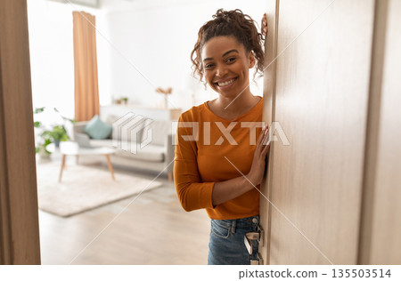 Joyful African American Female Opening Door And Smiling To Camera Standing At Home. Friendly Lady Meeting You In Doors Of Her House. Real Estate Property Ownership Concept 135503514