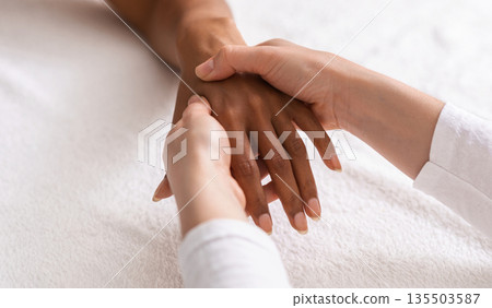 Masseuse making acupuncture hand massage for black woman at spa, view above, cropped Masseuse making acupuncture hand massage for black woman at spa, view above, cropped 135503587