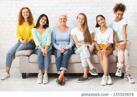 Mutiracial Ladies Of Different Age Sitting On Couch Posing And Smiling Together Indoor. Female Support And Equality Mutiracial Ladies Of Different Age Sitting On Couch Posing And Smiling Together Indoor. Female Support And Equality 135503658