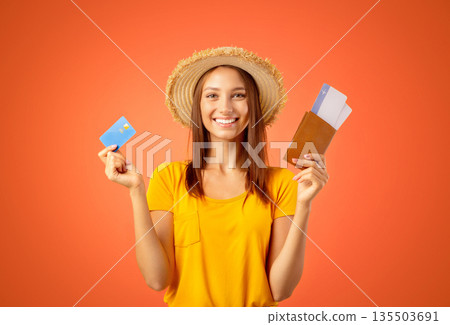 Joyful young woman in summer hat holding passport, flight tickets and credit card, yellow studio background. Happy lady traveller buying plane tickets online, getting loan for vacation or trip Joyful young woman in summer hat holding passport, flight tickets and credit card, yellow studio background. Happy lady traveller buying plane tickets online, getting loan for vacation or trip 135503691