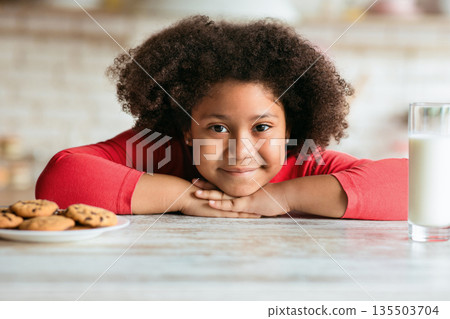 Curly African-American girl preferring cookies instead of milk for breakfast Curly African-American girl preferring cookies instead of milk for breakfast 135503704
