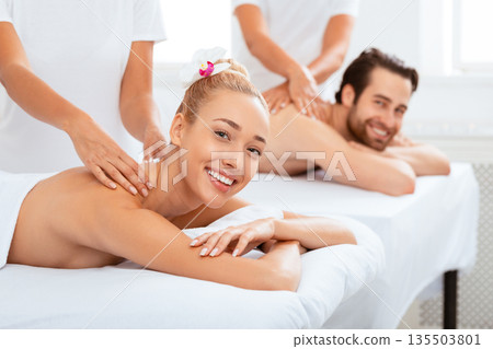 Married Couple Receiving Back Massage Together At Spa Salon, Smiling To Camera. Wellness, Beauty Treatment, Massage Therapy Concept. Masseurs Massaging Spouses For Relaxation. Selective Focus Married Couple Receiving Back Massage Together At Spa Salon, Smiling To Camera. Wellness, Beauty Treatment, Massage Therapy Concept. Masseurs Massaging Spouses For Relaxation. Selective Focus 135503801