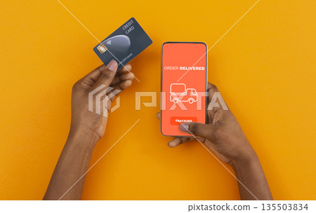 Stay at home, pay with credit card. African american man ordered with online app on cell phone, yellow background 135503834
