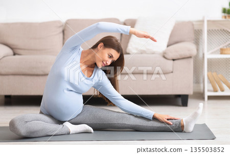 Pregnant Woman Stretching Arms And Legs, Doing Prenatal Workout At Home On Yoga Mat. Selective focus Pregnant Woman Stretching Arms And Legs, Doing Prenatal Workout At Home On Yoga Mat. Selective focus 135503852