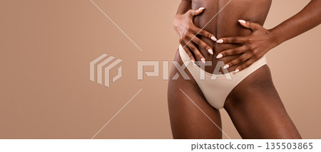 Fit Black Woman In Underwear Touching Belly While Posing Over Brown Studio Background, Cropped Image With Copy Space Fit Black Woman In Underwear Touching Belly While Posing Over Brown Studio Background, Cropped Image With Copy Space 135503865