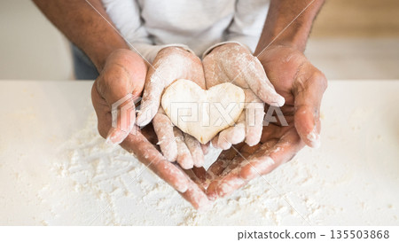 Happy childhood concept. Black man palms holding child palms with heart shaped cookie, panorama 135503868